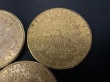 three gold coins sitting on top of each other on a black surface