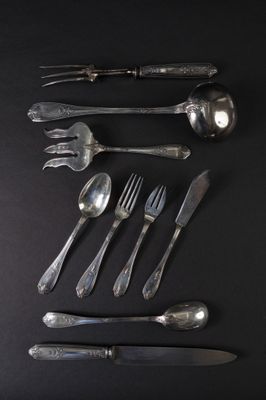 a lot of silver spoons and forks on a black table