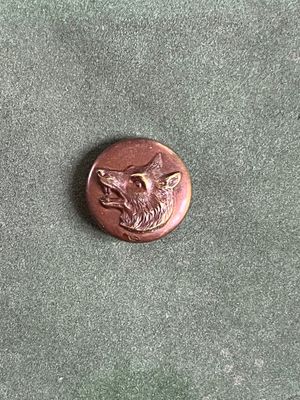 une image représentant un bouton en bronze orné d'une tête de loup