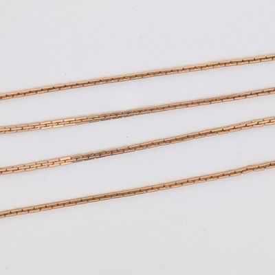 trois colliers à chaînes dorées posés sur une surface blanche