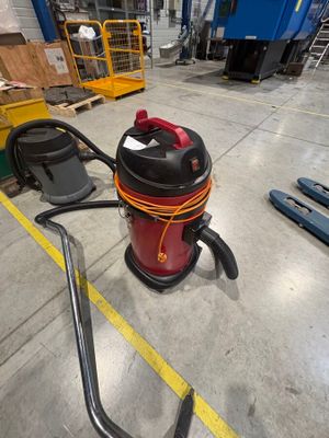 a red and black vacuum sitting on the floor in a warehouse