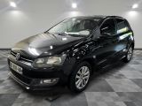 La Volkswagen Polo noire est garée dans une pièce au sol carrelé.