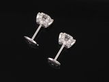 a pair of diamond earrings on a black surface