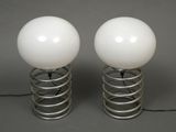 pair of white glass lamps sitting on top of a metal spring