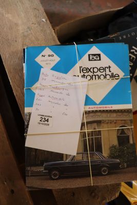 une pile de livres posée sur une table, avec une voiture en arrière-plan