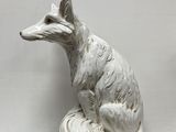 une statue blanche représentant un renard assis sur une table