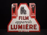 une vieille affiche publicitaire pour les appareils de cinéma Lumière, en rouge et blanc