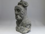 sculpture of a man ' s head on a rock on a gray background
