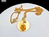 gold plated necklace with a golden rose pendant and a gold chain on a white surface