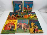 six vintage tarzan comic books are lined up on a white surface
