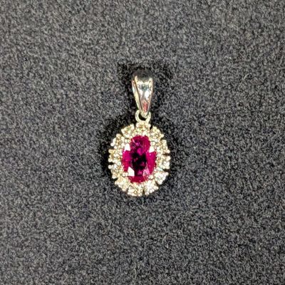 un gros plan d'un pendentif orné d'un diamant rose et blanc sur une surface noire