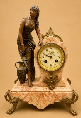 une statue représentant une femme debout à côté d'une horloge