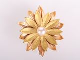 broche en forme de fleur de couleur dorée, ornée d'une perle au centre