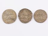 three silver coins sitting next to each other on top of a white surface