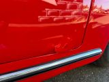 un gros plan d'une voiture rouge avec un mur de briques en arrière-plan