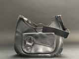 grey leather purse with a black strap on a gray background