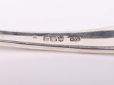a silver spoon with a handle on a white surface