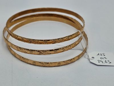 trois bracelets rigides en or avec une étiquette de prix sur un fond blanc