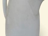 a white pitcher with a handle sitting on a table