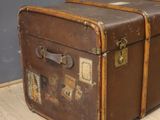 a brown suitcase sitting on the floor in front of a gray wall