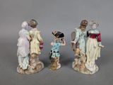 three figurines of women and a child are standing in front of a gray background
