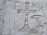 une plaque en pierre sur laquelle est gravée une croix, fixée sur le mur d'un immeuble