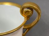 a white cup with a gold handle on a table