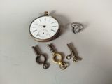 une petite montre de poche et plusieurs clés posées sur la table