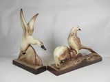 two figurines of birds sitting on top of each other on a table