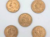 six gold sovereigns of different sizes and shapes on a white surface