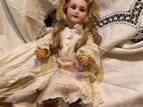 a doll that is sitting on a bed with a white sheet