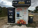 un distributeur automatique sur lequel est posée une pizza, au milieu de la route