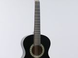 an image of a black acoustic guitar hanging on a white wall