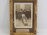 une vieille photo montrant un groupe d'hommes rassemblés autour d'un cercueil
