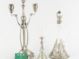 three silver candlesticks and a glass vase on a table