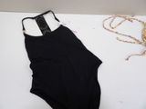 black one piece swimsuit laying on a white surface next to a necklace