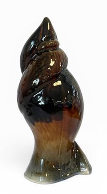 un objet de couleur marron et noire en forme de coquillage posé sur une surface blanche