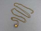 a close up of a gold necklace with a chain on a gray surface