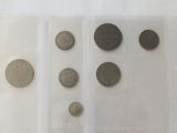 several coins are in a clear plastic case on a white surface