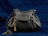 un sac à main noir posé sur un tissu bleu
