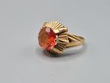 an image of a gold ring with an orange stone in the center