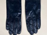 pair of black leather gloves sitting on top of a white table
