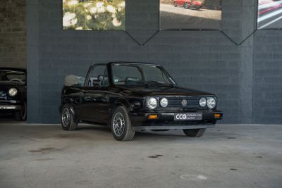 une voiture noire garée dans un garage à côté d'une voiture rouge