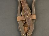 brown leather sheathed knife with two knives in it on a black surface
