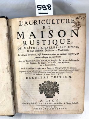 un vieux livre est ouvert sur une surface blanche, avec une étiquette accrochée dessus