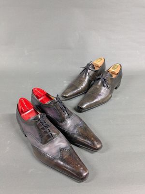 pair of men ' s shoes with red soles on a grey surface