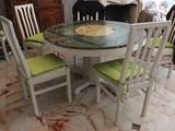 a table and chairs in a room with a painting on the table