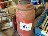 une grande bouteille rouge posée sur une table, sur laquelle figure le chiffre 6