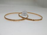 two gold bracelets on a white surface with a price tag