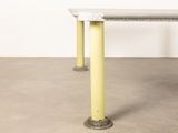 a concrete table with yellow legs in a room